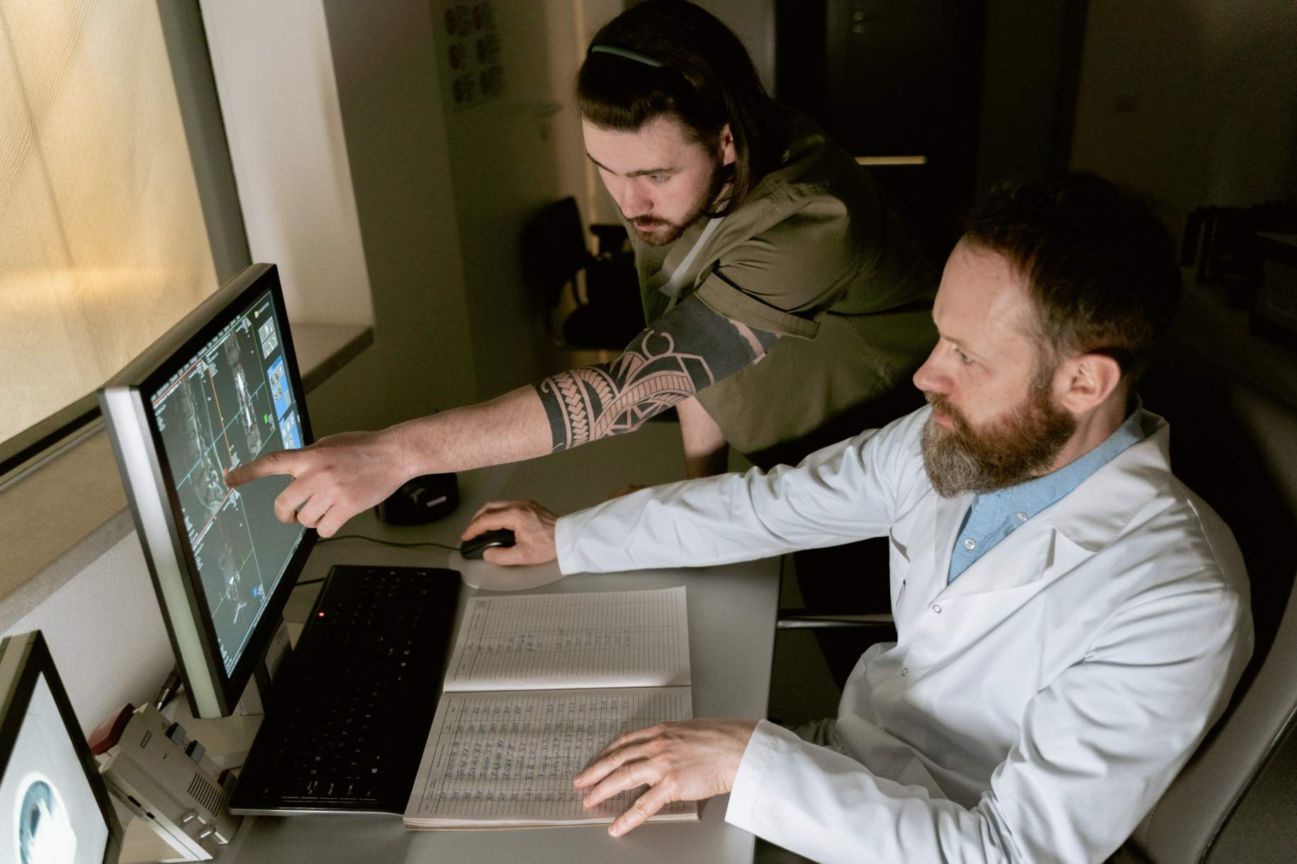 A radiologist and radiology technician reviewing a study together at a digital workstation