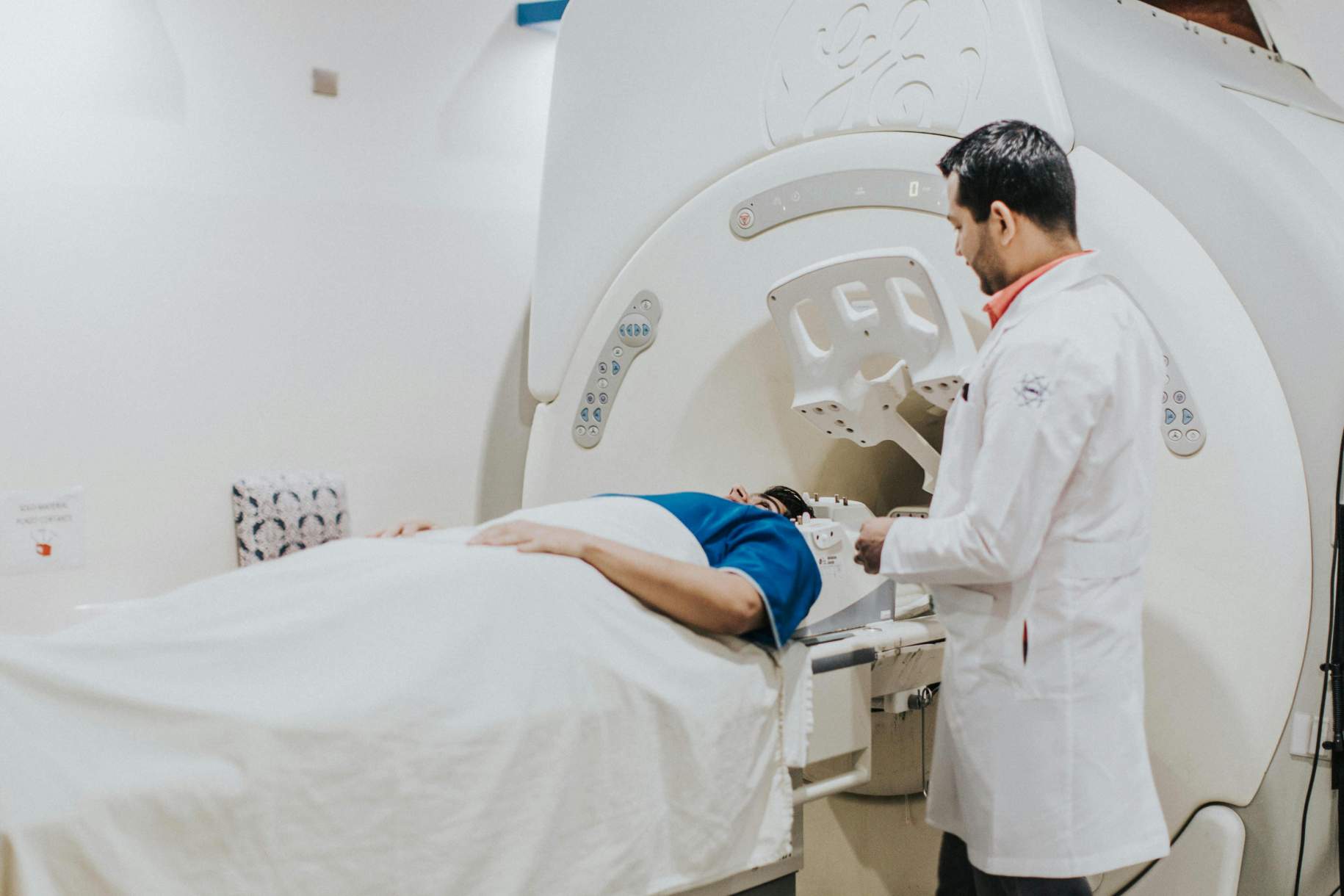
                                    
                                        A clinician in a lab coat explains the procedure to a patient lying on an MRI machine table.
                                    
                                